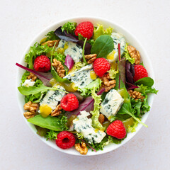 Salad with lettuce roquefort cheese raspberries walnuts and vinaigrette on white background