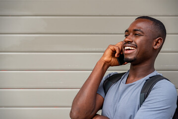 Afro young man using mobile phone against a wall