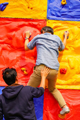 Man climbing wall without grips. Businessman climb on colourful wall