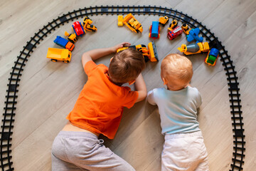 Obraz na płótnie Canvas Preschool boys playing with educational toys - blocks, train, railroad, vehicles at home or daycare. Toys for preschool and kindergarten. Top view