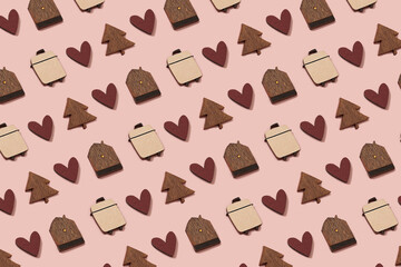 Wooden Christmas ornaments and symbols of a festive holiday season. Christmas tree, red heart, suitcase and a house mini toys flat lay with copy space on a pastel pink background. Pattern.