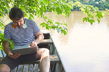 Programmierer arbeitet am Laptop Computer am See