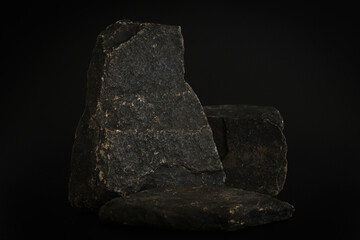 Rock podium on the black background. Stone podest for product, cosmetic presentation. Creative mock up. Pedestal or platform for beauty products.