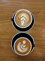 Two cups of cappuccino on a wooden table top vertical view