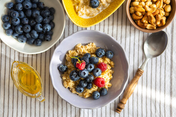 Oatmeal with berries and honey for breakfast.Oatmeal with coconut milk and berries.Healthy and trendy breakfast. Schoolchild's breakfast.Delicious porridge with berries and syrup for proper nutrition.