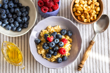 Oatmeal with berries and honey for breakfast.Oatmeal with coconut milk and berries.Healthy and trendy breakfast. Schoolchild's breakfast.Delicious porridge with berries and syrup for proper nutrition.