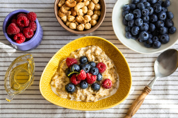 Oatmeal with berries and honey for breakfast.Oatmeal with coconut milk and berries.Healthy and trendy breakfast. Schoolchild's breakfast.Delicious porridge with berries and syrup for proper nutrition.