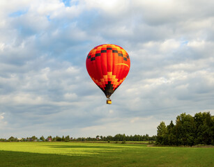 Big beautiful single hot balloon fly high in the sky over scenery green field and forest. Extreme entertainment for vacation and leisure.