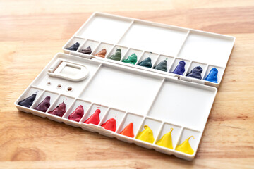 Watercolor paints set. Color in watercolor palette dirty on wooden background.