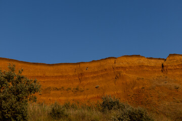 Geology. Desert landscape. Panorama view of the sandstone formation, the rocky cliffs, sand. Background or texture of sandy cliff on the coast, orange limestone