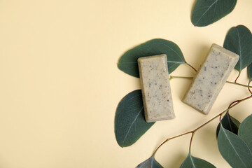 Flat lay of soap bars and green leaves on beige background, space for text. Eco friendly personal care product