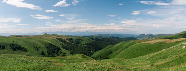 Obraz premium Panoramic view of green hills and blue mountains