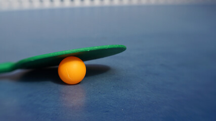 Ping pong paddle and ball on a table. Blurred background with copy space.