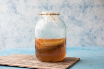 Raw fermented homemade alcoholic or non alcogolic kombucha superfood. Ice tea with healthy natural probiotic in glass with mint on  blue background