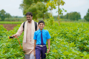 Young indian farmer with his son at green agriculture field.