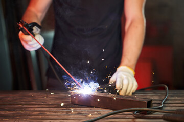 inverter welding machine at work. male hands in gloves weld two pieces of iron with sparks