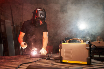 a welder in a protective helmet works with a welding machine. sparks fly