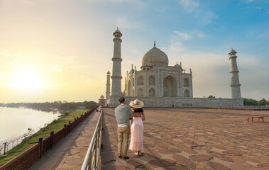 Taj Mahal Agra historic white marble mausoleum at sunrise with view of tourist couple enjoying the...