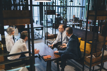 Colleagues having business meeting on couch in office lounge zone