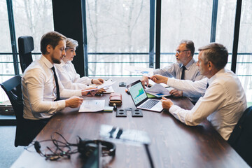 Businesspeople speaking and working at table with laptop