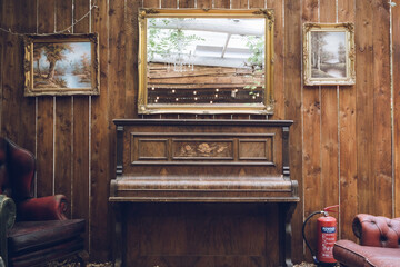 Fototapeta na wymiar A rustic antique piano with a mirror above and a weathered wooden wall