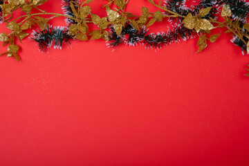 Composition of christmas decorations with garland and copy space on red background