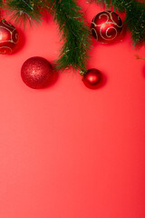 Composition of garland with baubles and copy space on red background