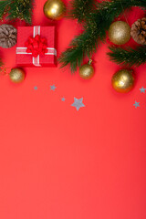 Composition of garland with baubles, presents, pine cones and copy space on red background