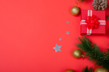 Composition of garland with baubles, presents and copy space on red background