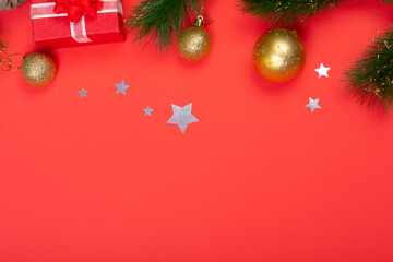 Composition of garland with baubles, presents and copy space on red background