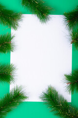 Composition of white card with copy space framed with fir tree branches on green background