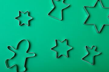 Composition of star and angel ginger man cookie cutters on green background
