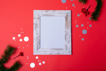 Composition of white card in frame with copy space and christmas decorations on red background