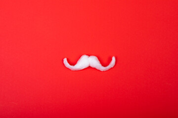Composition of white santa claus moustache with copy space on red background