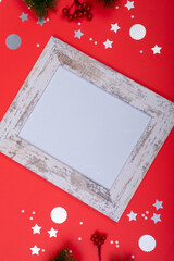 Composition of white card in frame with copy space and christmas decorations on red background
