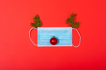 Composition of face mask with christmas decorations in shape of reindeer on green background