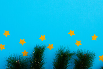 Composition of fir tree branches with stars and copy space on blue background