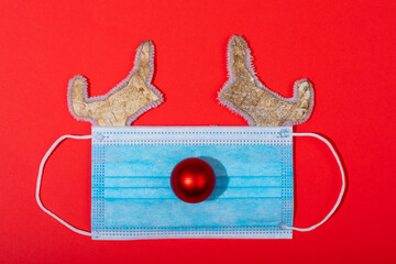 Composition of face mask with christmas decorations in shape of reindeer on green background