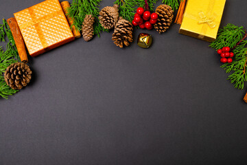 Composition of christmas decorations with presents, pine cones and copy space on black background