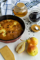 Homemade pear pie on a white table with pears in the foreground