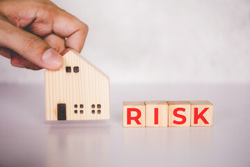 Planning with finance and investment of business about real estate with risk and safety of insurance, uncertainty for economy, hands put home and cube wooden block with word RISK, business concepts.