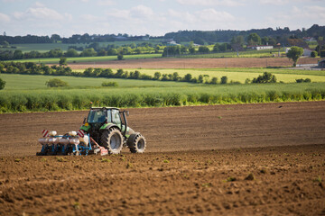 Obraz premium Paysage agricole, tracteur travaillant la terre au champ.