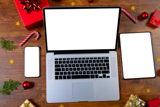 Composition of smartphone, laptop, tablet with copy space and decorations on wooden background