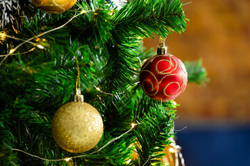 Composition of christmas tree with red and gold baubles on blurred background