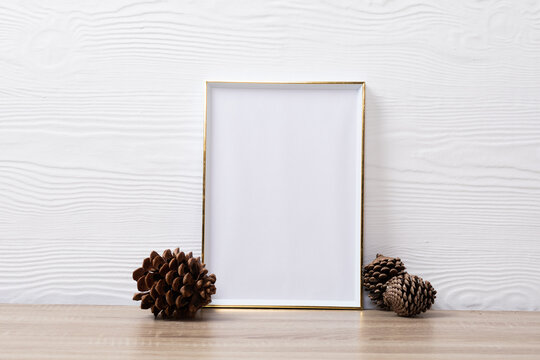Composition of white card in frame with copy space and pine cones on white background
