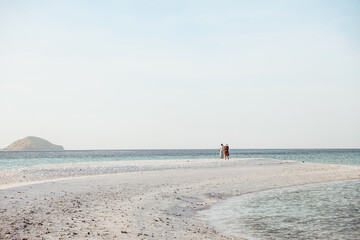 Two women tourist walking on the white sand beach