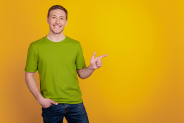 Portrait of young guy showing finger empty blank space ad select suggest isolated on yellow color background