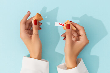 Creative composition for shopping sale. Women hands with manicure holding fortune cookie