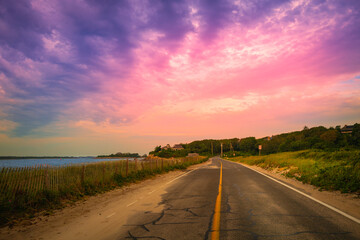 Pink sunrays and purple clouds in the dramatic sky after rain over the Nobska Beach road on Cape...