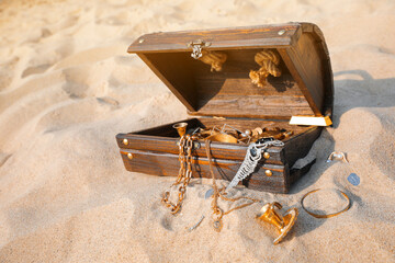 Open wooden treasure chest on sand, space for text